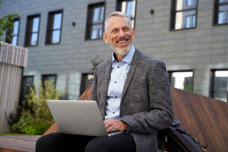 Ideas for business. Portrait of cheerful elegant middle aged businessman smiling while working on